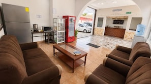 A hotel lobby with brown sofas, a wooden coffee table, a refrigerator, a microwave, a red vending machine, and a reception desk. - Hotel King del Centro San Miguel (San Miguel)