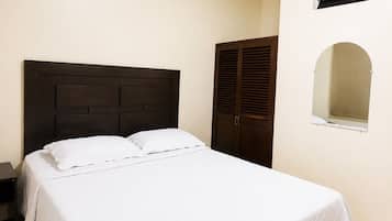A bedroom with a bed, a nightstand, a wardrobe, and a window with blinds.