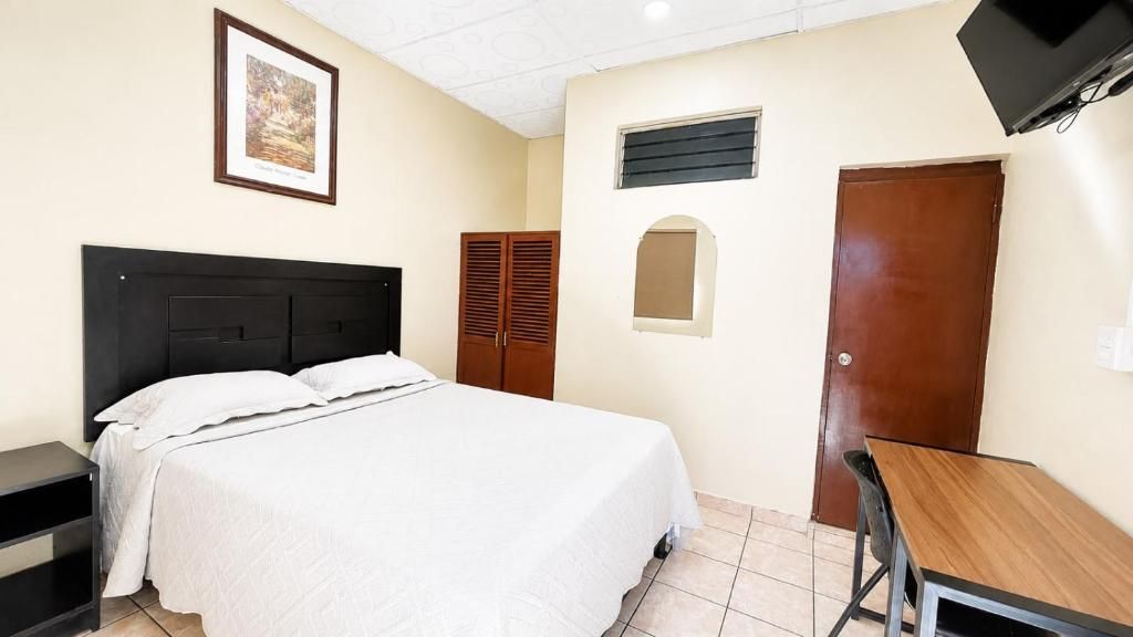 Une chambre à coucher comprenant un lit, un bureau, une armoire et un téléviseur.