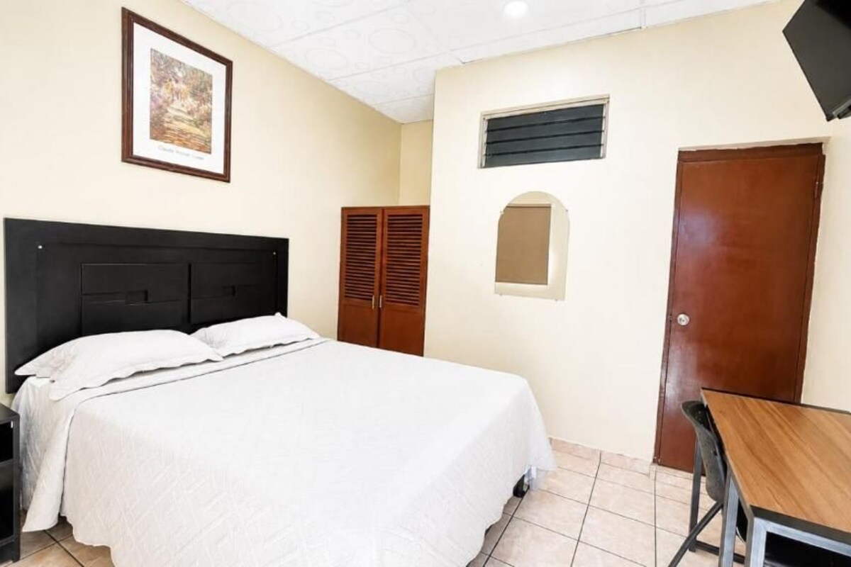 Un dormitorio con cama, escritorio, armario y televisor.