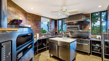 A commercial kitchen with a large oven, a stove, and a ventilation hood.