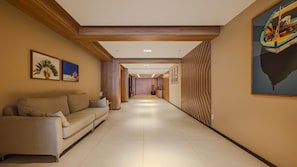 A hotel corridor with a sofa, framed artwork, and a patterned wall. - Apt w/ Pool & Gym, 800m from Armação Beach  Espanhol: (Salvador)