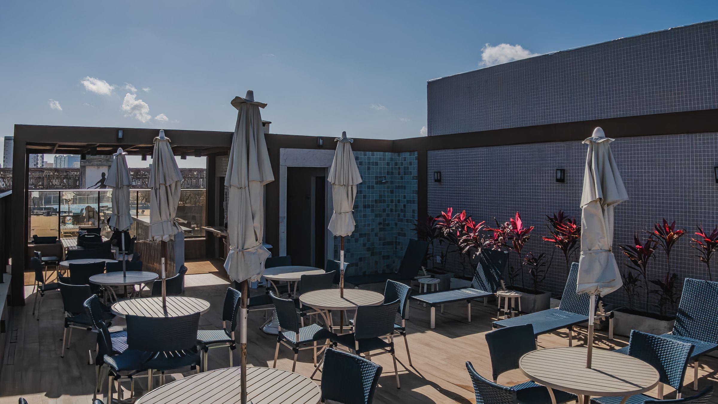 An outdoor patio with round tables and chairs, umbrellas, and potted plants.