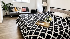 Ein Hotelzimmer mit einem großen Bett, einer Couch, einem Schreibtisch, einer Lampe und einem Fenster.