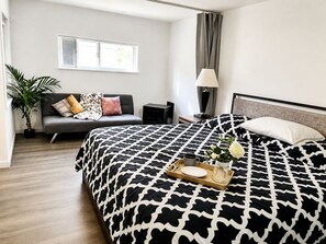 Et hotelværelse med en stor seng, en sofa, et skrivebord, en lampe og et vindue.