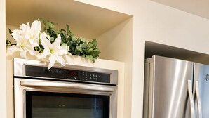A kitchen with a built-in oven and a stainless steel refrigerator.