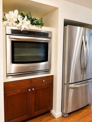 Una cocina con horno empotrado y refrigerador de acero inoxidable.