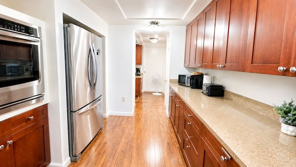 A kitchen with stainless steel appliances, wooden cabinets, and a granite countertop.