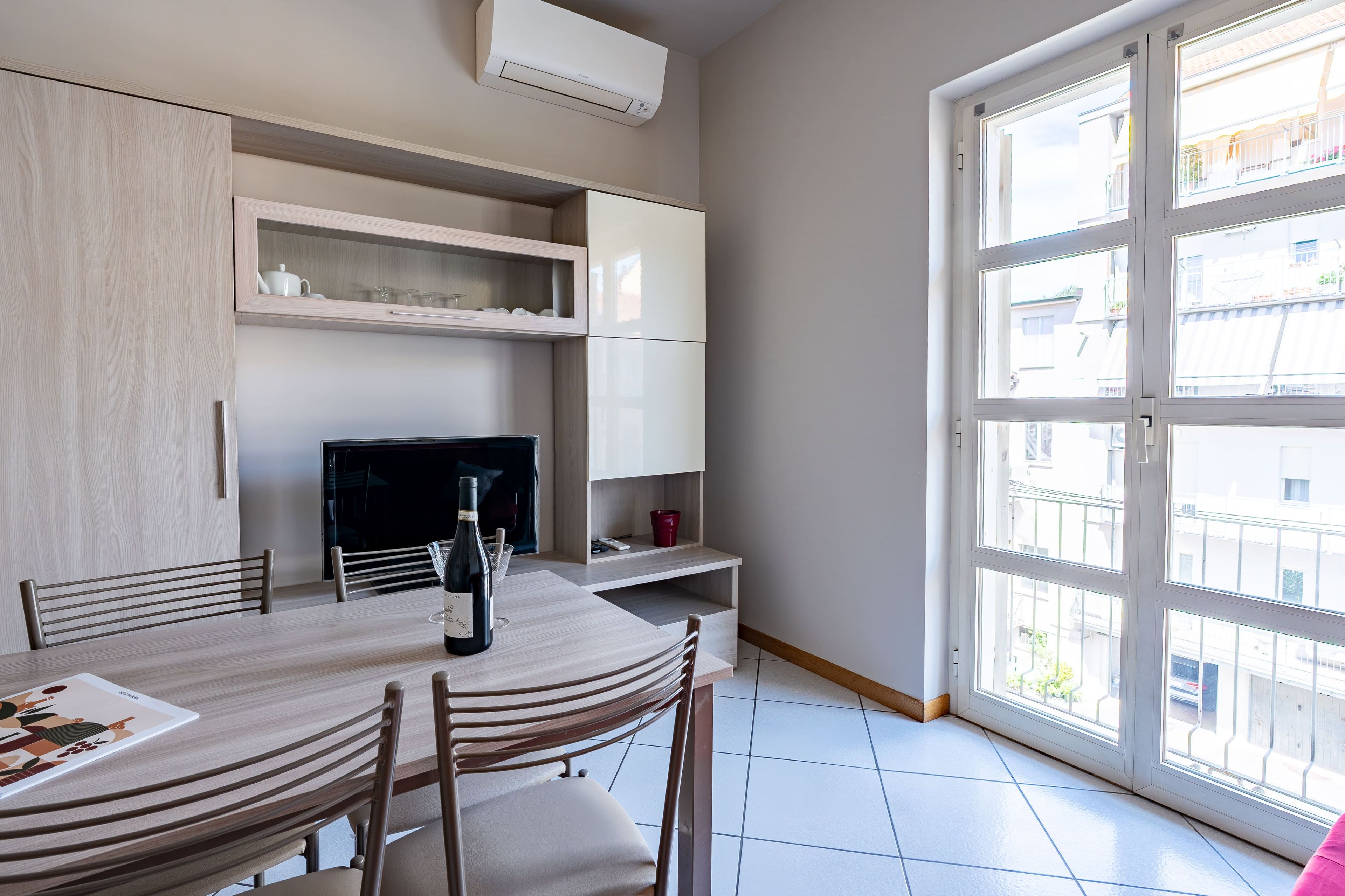 Una cocina moderna con comedor, televisor y un amplio ventanal.