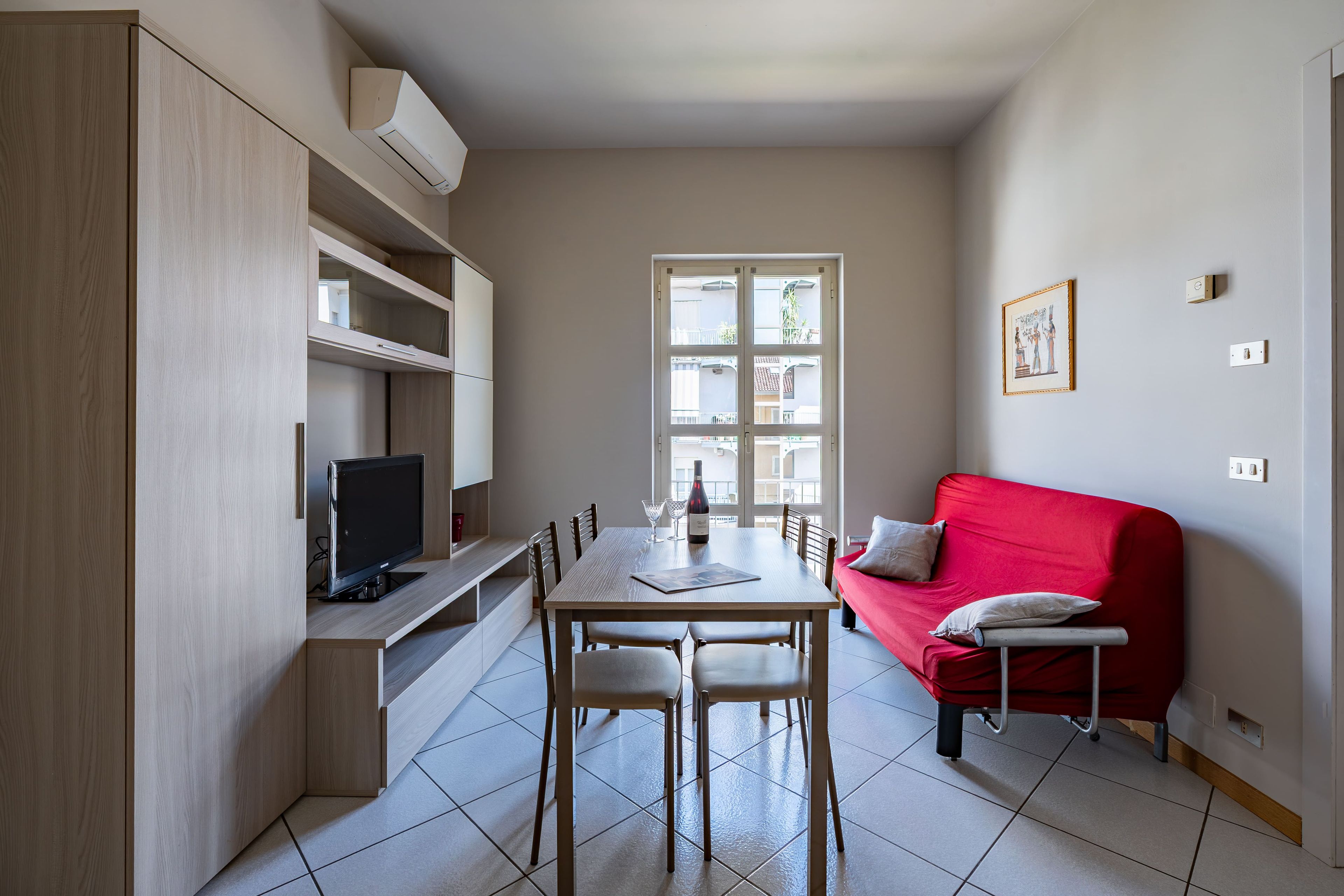 A compact living space with a dining area, a red sofa, and a television.