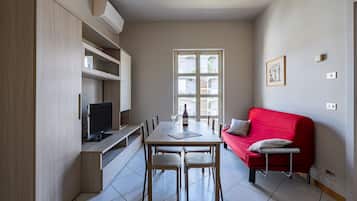 A compact living space with a dining area, a red sofa, and a television.