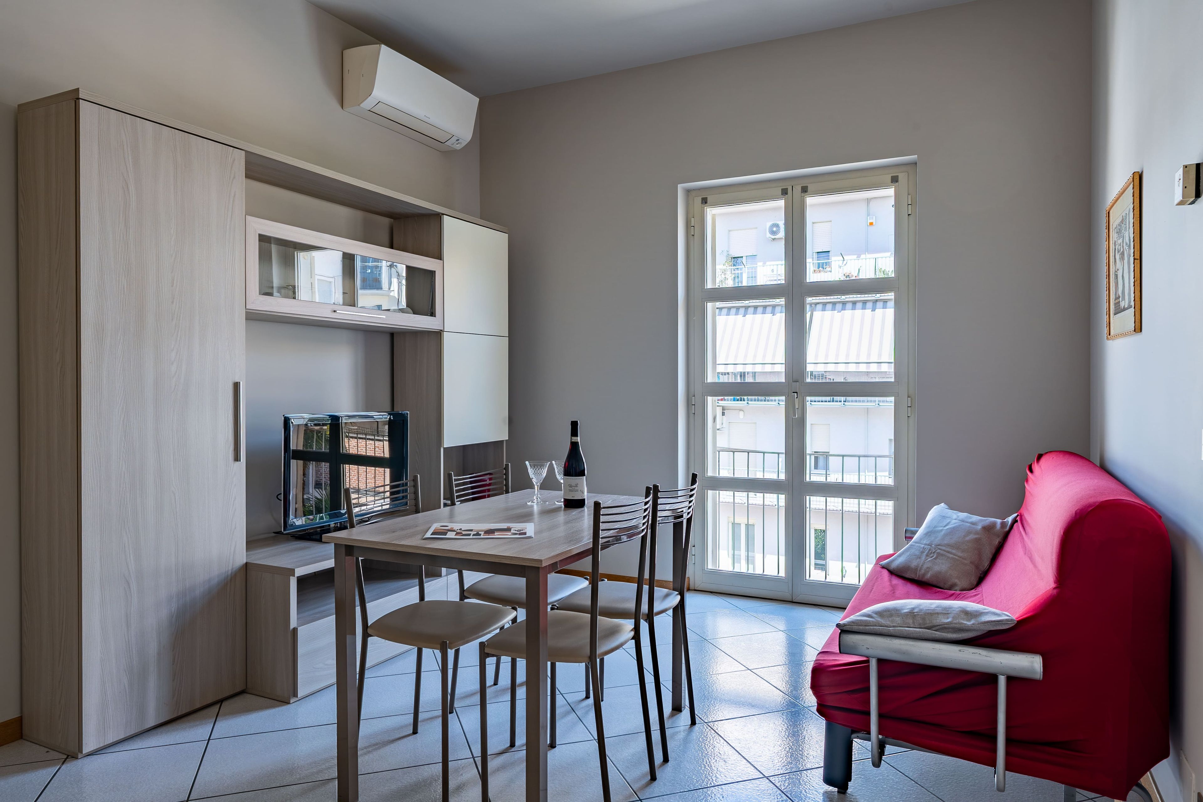 Un espacio habitable compacto con comedor, sofá rojo y ventana con vistas.