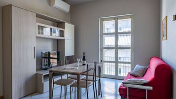 Un espacio habitable compacto con comedor, sofá rojo y ventana con vistas.