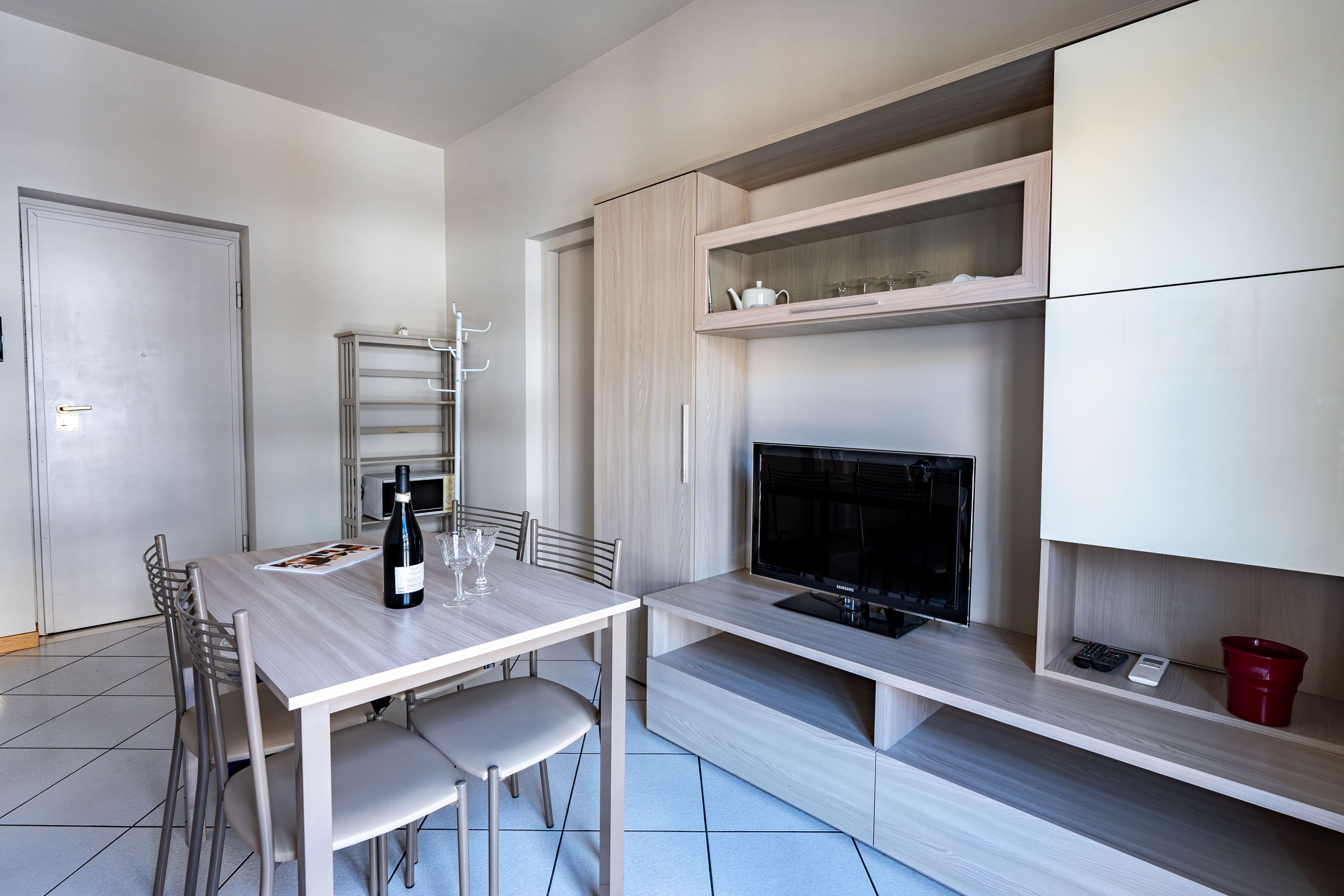A modern kitchen with a dining table, chairs, a wine bottle, and a television.