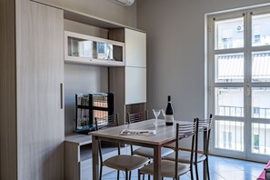 A modern kitchen with a dining table, chairs, a wine bottle, and a magazine. - Casa Savona nel cuore di Alba (Alba)