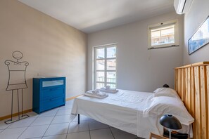 A bedroom with a bed, a dresser, a window, and a wall with a simple line drawing. - Casa Savona nel cuore di Alba (Alba)