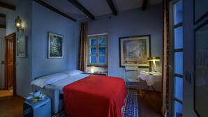 Ett hotellrum med en säng, ett sängbord, en lampa och konstverk på väggarna.
