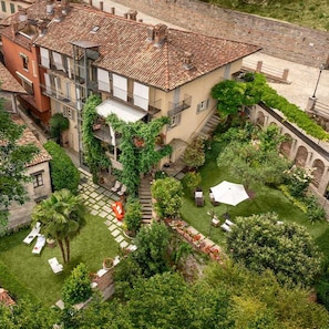 Un cortile con una scala centrale, circondato da vegetazione lussureggiante e arredi da esterno.