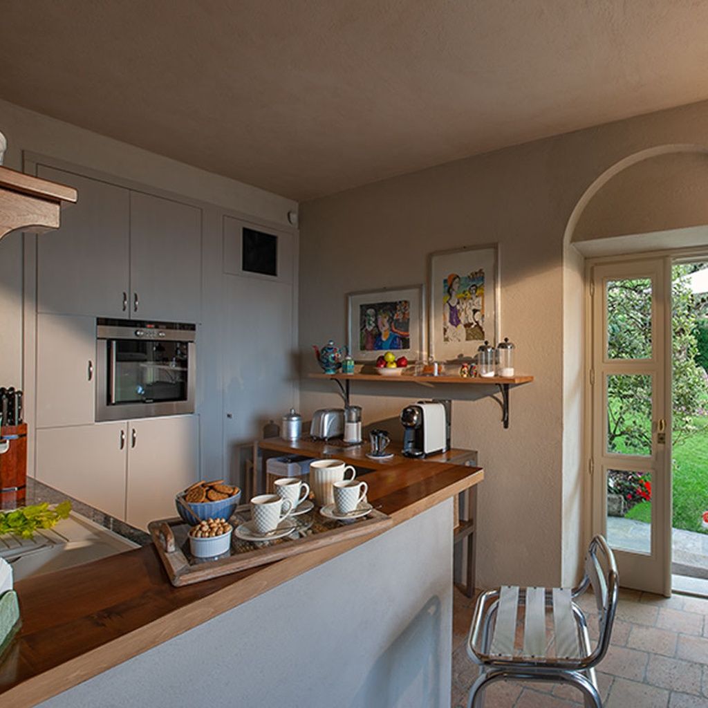 Cozinha com bancada de madeira, forno embutido e área de refeições com uma cadeira.