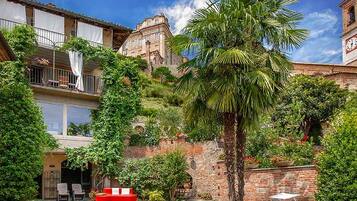 Une cour avec des fauteuils de jardin, un palmier et un bâtiment historique doté d’un clocher.