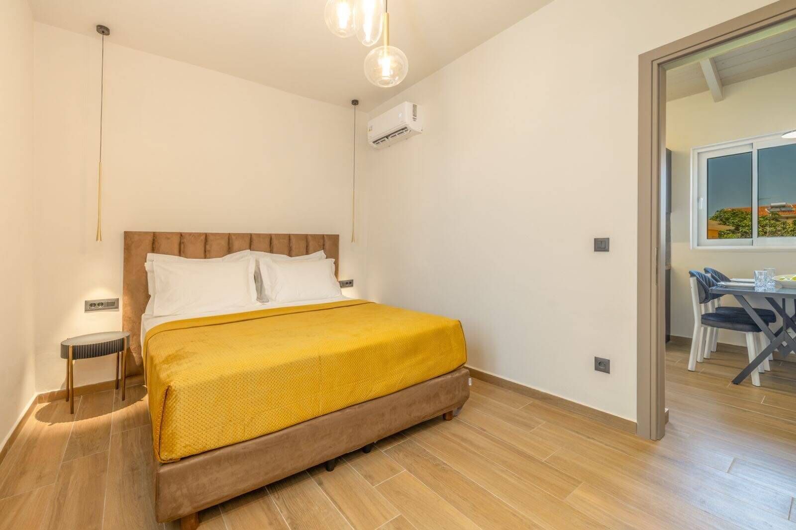 A hotel room with a bed, bedside table, and a view of the outside.