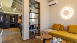 Ein modernes Wohnzimmer mit einer Couch, einem Couchtisch und einem Schreibtischbereich mit einem Stuhl. Eine Treppe führt zu einer weiteren Ebene.
