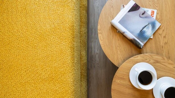 Ein runder Holztisch mit zwei weißen Kaffeetassen und einer Zeitschrift.
