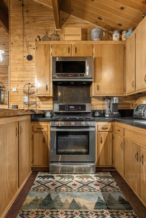 A kitchen with wooden cabinets, a built-in oven, a microwave, and a coffee maker. - Heavenly Bay Retreat | Hot Tub, Lake View & Games! (Big Bear Lake)