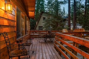 A wooden deck with outdoor seating and a railing, surrounded by trees. - Heavenly Bay Retreat | Hot Tub, Lake View & Games! (Big Bear Lake)