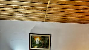 A bedroom with a wooden bed, white bedding, a framed landscape painting, and two bedside lamps. - Aramat La Joya (Calarcá)