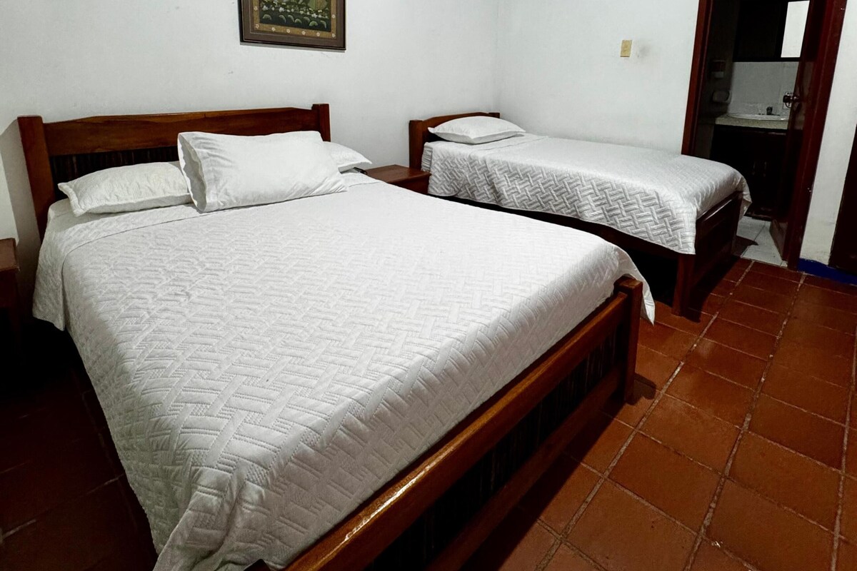 Ein Schlafzimmer mit zwei Holzbett, einer Holzbalkendecke und einem Fliesenboden.