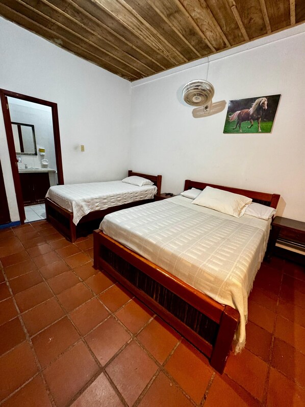 A bedroom with two beds, a wooden ceiling, a tiled floor, a wall-mounted fan, and a picture of a horse.