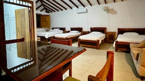 A room with a sloped ceiling, wooden beams, and multiple beds arranged in a row. - Aramat La Joya (Calarcá)
