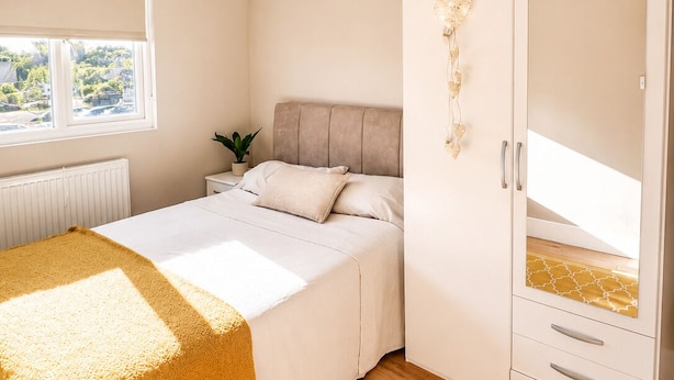 A bedroom with a bed, a wardrobe, a radiator, and a window. - 4-Bed | New Cross to Central London in 20 Mins (London)