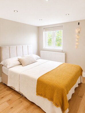 A bedroom with a bed, a window, a radiator, and a wall-mounted light fixture. - 4-Bed | New Cross to Central London in 20 Mins (London)