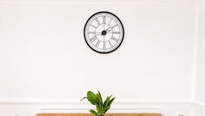 A dining table with two chairs, a potted plant, and a wall clock. - 4-Bed | New Cross to Central London in 20 Mins (London)