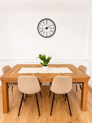 A dining table with two chairs, a potted plant, and a wall clock. - 4-Bed | New Cross to Central London in 20 Mins (London)