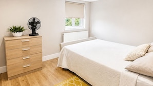 A bedroom with a bed, a dresser, a radiator, a window, and a fan. - 4-Bed | New Cross to Central London in 20 Mins (London)