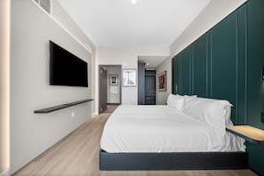 A modern bedroom with a bed, a TV mounted on the wall, and a hallway leading to another room. - Luxury E11EVEN Skyline Views & ELITE Amenities (Miami)