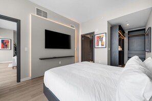 A modern hotel room with a large bed, a flat-screen TV mounted on the wall, a walk-in closet, and a bathroom visible through an open door. - Luxury E11EVEN Skyline Views & ELITE Amenities (Miami)
