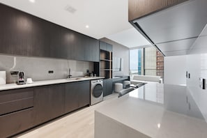 A modern kitchen with dark wood cabinets, a stainless steel range, and a built-in washing machine. - Luxury E11EVEN Suite with Amazing Pool & Views (Miami)