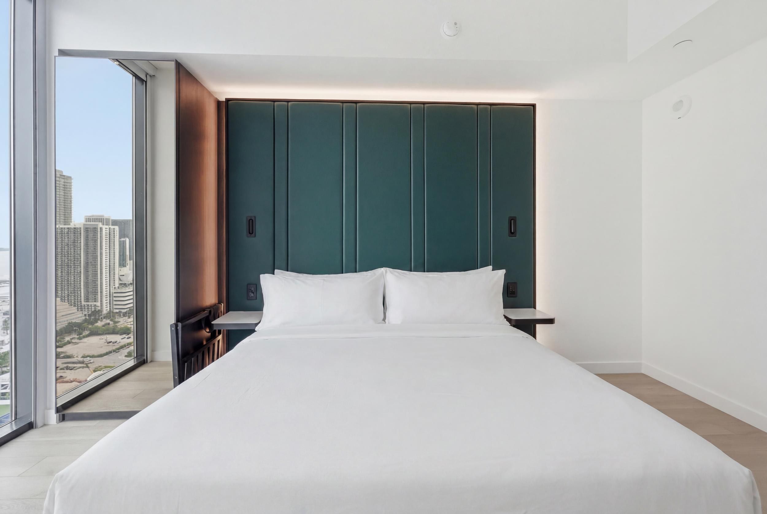 Een moderne hotelkamer met een groot bed, uitzicht op de stad en een groot raam.