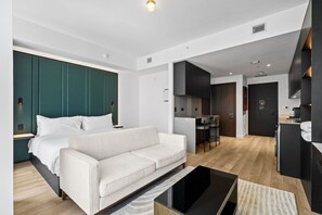 A modern hotel room with a white sofa, a glass coffee table, and a kitchenette area. - Luxury E11EVEN Suite with Elite Pool & Views (Miami)