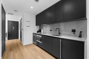 A modern kitchen with dark cabinetry, a stainless steel sink, and a built-in oven. - Luxury Miami Studio with Rooftop Pool and Views (Miami)