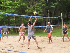 Un grupo de personas jugando voleibol de playa en una cancha de arena con una red azul.