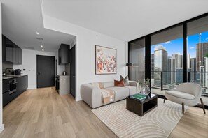 Een modern appartement met woonkamer, keuken en een groot raam met uitzicht op de stad.