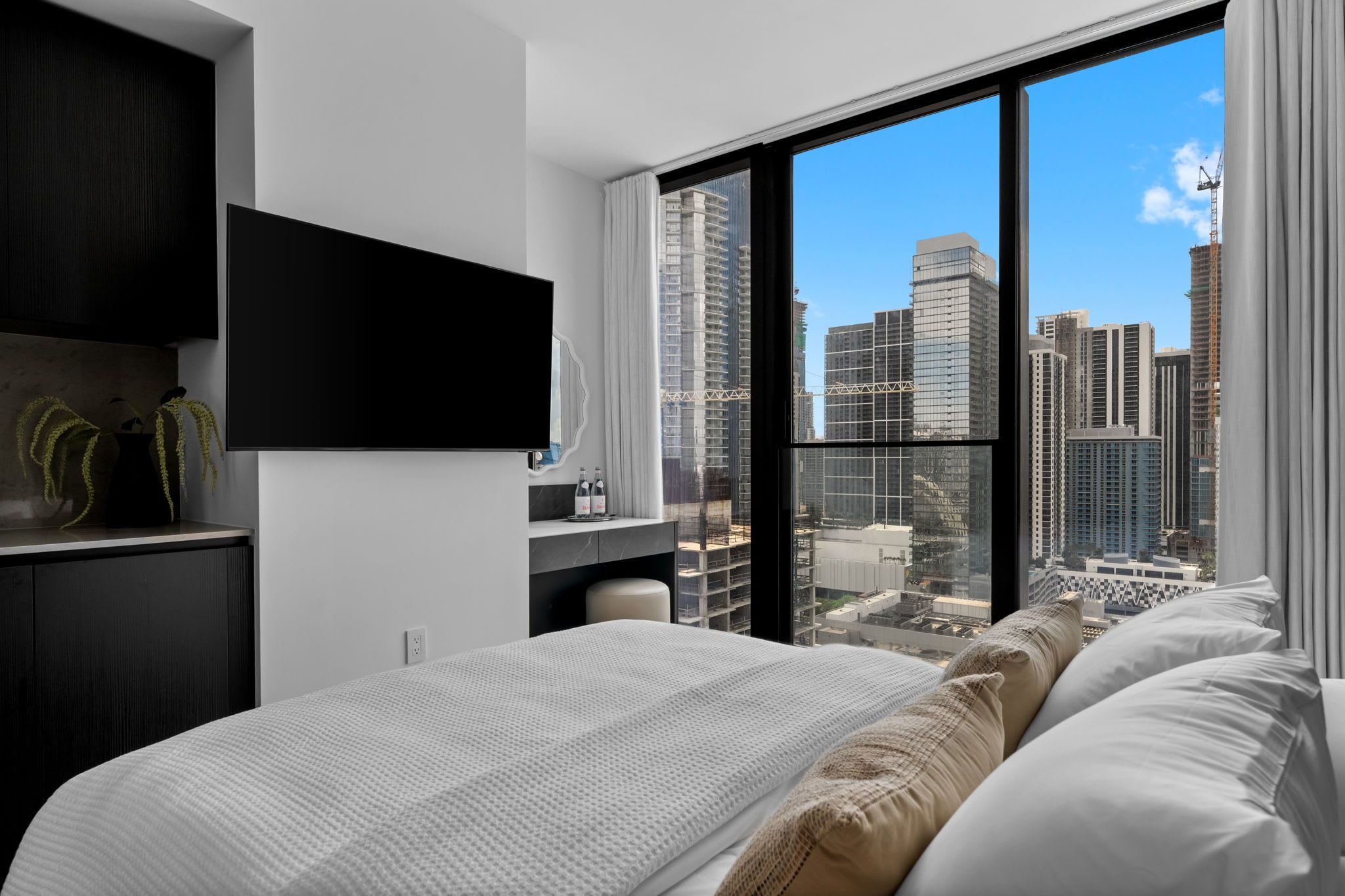 Una habitación de hotel moderna con una cama grande, un escritorio y un televisor montado en la pared.