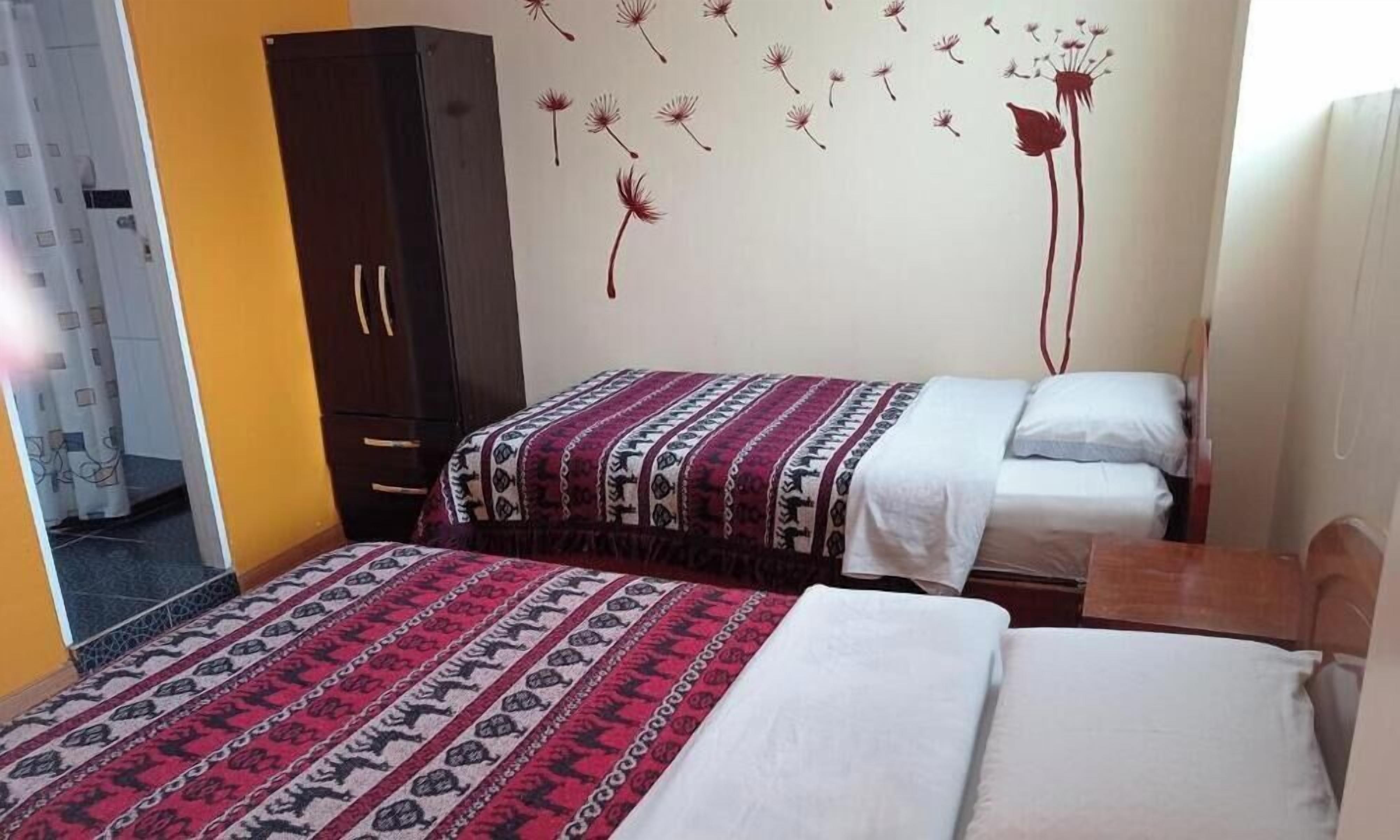 Una camera da letto con due letti, un armadio e una parete decorata con adesivi a tema tarassaco.
