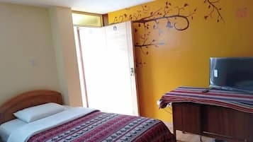 A bedroom with a bed, a dresser, a television, and a door.