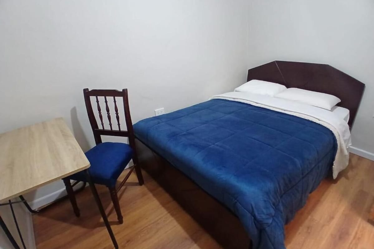 A bedroom with a bed, a wooden chair, and a small table.